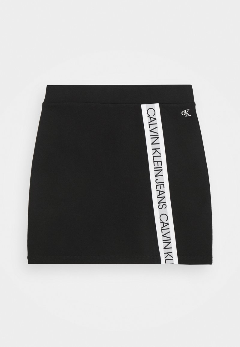 Mini-jupe noire avec une bande verticale blanche sur le côté portant le texte "Calvin Klein Jeans" et un petit logo "cK" près de la ceinture.