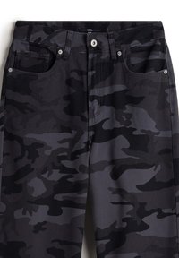 Black camo pants with a cotton fabric blend. Features front pockets, a button closure, and a textured surface with varying shades of gray.