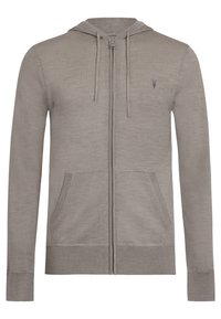 Haut à capuche zippé gris avec cordon de serrage, poches avant et bords côtelés au niveau des poignets et de l'ourlet. Présente un logo subtil sur la poitrine gauche. Texture de tissu douce.