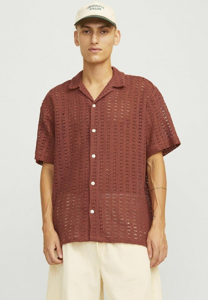 Camisa de manga corta de punto abierto en color óxido con cierre de botones en la parte delantera y un ajuste relajado. Presenta un cuello y una textura ligera.