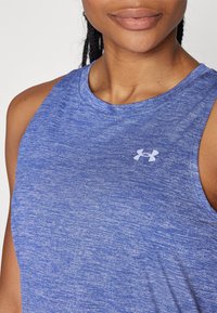 Blå tanktopp i texturerad tyg, med rundad halsringning och en liten vit Under Armour-logotyp på bröstet.