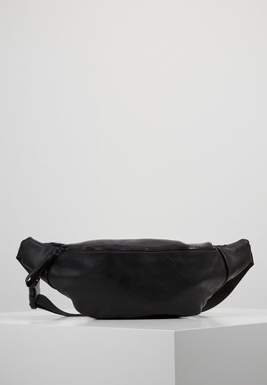 Banane en cuir noir avec fermeture éclair et sangle réglable, présentée sur un socle blanc sur fond uni.