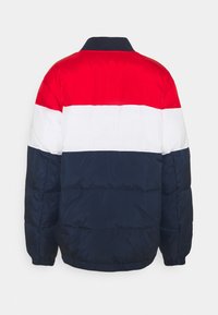 Prešívaná bunda s farebnými blokmi: červené, biele a námornícke modré časti. Má rebrovaný golier a elastické manžety, vyrobená z hladkej, ľahkej látky.