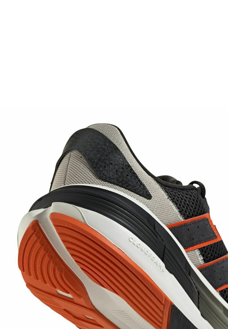 Scarpa sportiva con tomaia in mesh grigio, dettagli neri, strisce arancioni e suola in gomma testurizzata. Presenta il marchio "CLOUDFOAM" sul lato.