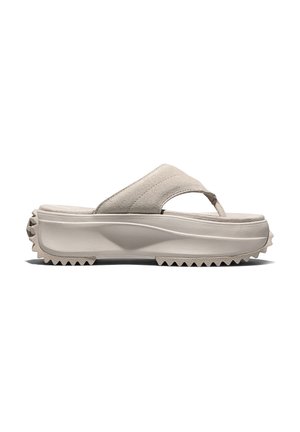 Sandalia beige tipo chancla con plataforma, suela gruesa, parte superior de ante y dibujo en la suela en forma de dientes para mejor agarre, vista de perfil lateral.