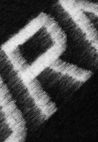 Wollen stof in zwart en wit met een fuzzy textuur, featuring een geometrisch patroon van vervaagde rechthoeken in contrasterende kleuren.