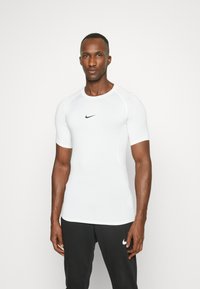 Camiseta deportiva blanca de manga corta, con un diseño ajustado y el logo negro de Nike en el pecho. Tejido suave y acentos de costura en contraste.