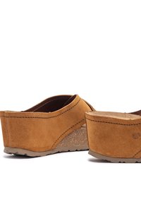 Brown suede clogs with a slightly elevated cork-like wedge heel, featuring a curved design and minimal stitching detail.