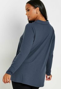 Långärmad, ribbad topp i mörkblått. Har en kragad hals, något lös passform och textilstruktur. Enfärgad design utan mönster.