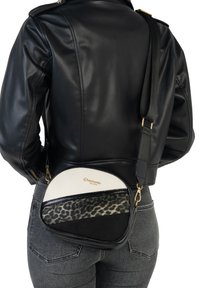 Sort læder crossbody taske med en buet form, der har en hvid toppanel, en sektion med leopardmønster og detaljer i guld hardware.