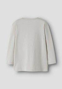 Enkel, offwhite långärmad skjorta visad bakifrån med rund halsringning, på en ljust grå bakgrund.