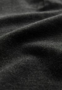 Gros plan d'un tissu noir doux avec une texture fine visible et des plis délicats créant des ombres et des reflets subtils.