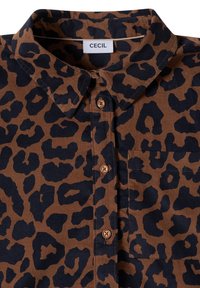 Chemise en velours côtelé marron avec motif léopard noir, col pointu, boutons sur le devant et poche poitrine étiquetée "Cecil."