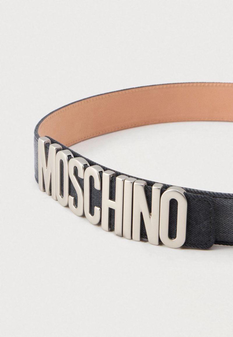 Cintura in tessuto nero con grandi lettere argentate che spellingano MOSCHINO sulla parte anteriore e un rivestimento interno in pelle beige chiaro.