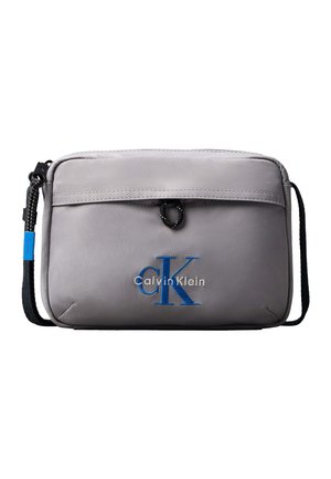 Geantă crossbody dreptunghiulară gri deschis cu bretea neagră reglabilă și logo albastru "CK Calvin Klein" pe buzunarul frontal.