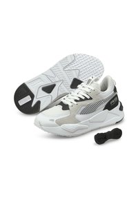 Zapatillas deportivas blancas y grises con materiales de malla y ante, una suela de goma negra texturizada y un acento negro contrastante en el talón.
