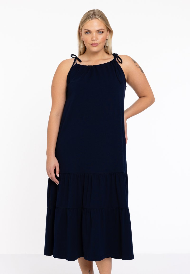 Navyblaues ärmelloses Kleid mit einem gestuften Saum, weichem Stoff und verstellbaren Fesselriemen an den Schultern. Geschmeidige Textur über das gesamte Kleid.