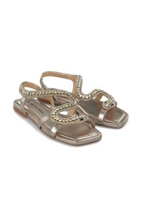 Metalen gouden platte sandalen met een vierkant teen, voorzien van decoratieve beaded banden in een golvend patroon voor extra detail en accent.
