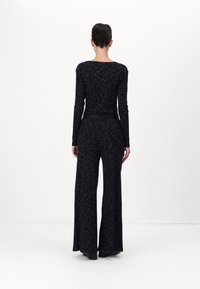 Zwart, lange mouw jumpsuit met een slim fit top en wijde broekspijpen, met een gemêleerd patroon en een ceintuur in de taille. Gladde stofafwerking.