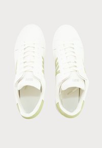 White sneakers with light green accents, featuring a smooth leather finish, round toe, and classic lace-up design.