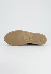 Tan rubberen zolen met een gestructureerde grip, voorzien van een circulair logo dat zichtbaar is nabij de hiel en een patroon op het oppervlak voor extra grip.