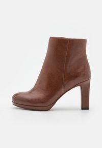 Hnědé kožené kotníkové boty s zaoblenou špičkou, hladkým povrchem, elegantním designem a štíhlým vysokým podpatkem. Minimalistický styl bez viditelných ozdob.