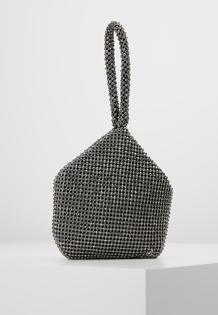 Petit sac de soirée noir recouvert de perles métalliques avec une anse en boucle, posé debout sur un socle blanc.