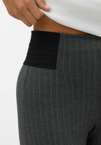 Pantalones gris a rayas con una banda elástica negra texturizada en la cintura, con un ajuste ceñido y detalles de costura ligera.