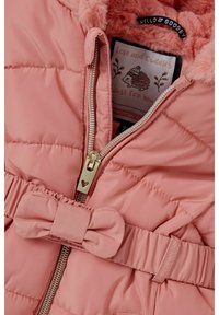 Růžová prošívaná bunda s měkkou, chlupatou podšívkou, zipem se zlatým srdíčkem a páskem v pase s detailním mašlovým zdobením.