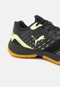 Fekete sportcipő neon sárga kiegészítőkkel és textúrált felülettel. Gumitalpa van, amely tapadást biztosít, kapcsos dizájnja van és márkázott részletekkel rendelkezik.