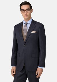 Jūras flotes pinstripes uzvalks ar divu pogu aizdari, sakostām atlokiem un divām priekšējām kabatām. Pārklāts ar gaiši zilu kreklu un brūnu vestu.