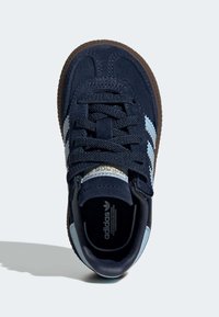 Námořnicky modrá teniska s broušeným svrškem, světle modrými pruhy, texturovanou hnědou gumovou podrážkou a černými tkaničkami. Na jazyku je značka.