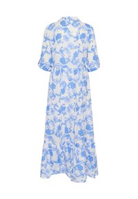 Lång, vit klänning med blå blommönster, krage och 3/4-långa ärmar. Har en flödande design med flera lager i nederkant och mjuk, lättviktig tyg.