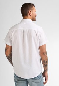 Witte korte mouwen overhemd met een button-down kraag en een kleine plooi aan de achterkant, gemaakt van een lichte stof. Bevat subtiele stiksels en een label.