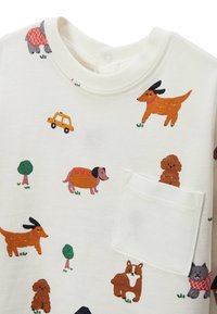 Chemise blanche à manches courtes présentant des motifs colorés de chiens et de voitures. Comprend une poche poitrine et un col rond, fabriquée en tissu en coton doux.