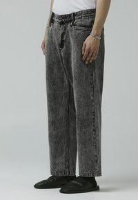 Denim jeans i falmet svart farge, med løs passform, høy midje og subtile slitasjer. Inkluderer front- og baklommer.