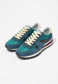 Niebiesko-zielone trampki z cholewką z zamszu i tkaniny, faliste detale, beżowe sznurowadła oraz bordowy pasek na śródpodeszwie. Czarna podeszwa zewnętrzna.