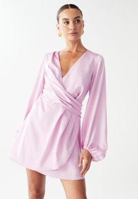 Roza satenska obleka z globokim V-izrezom, dolgimi napihnjenimi rokavi in cinčeno pasom. Ima nabran detajl in gumbaste poudarke ob strani.