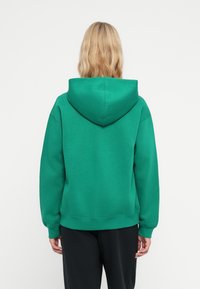 Sudadera con capucha verde de corte relajado, con puños y dobladillo de canalé, elaborada en una suave mezcla de algodón. Presenta una capucha grande.