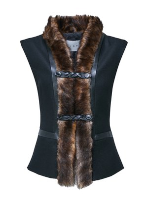 Femme portant un haut sans manches noir avec une bordure en fourrure marron, un pantalon noir, des talons noirs, et tenant un grand sac à main en fourrure noire et marron.