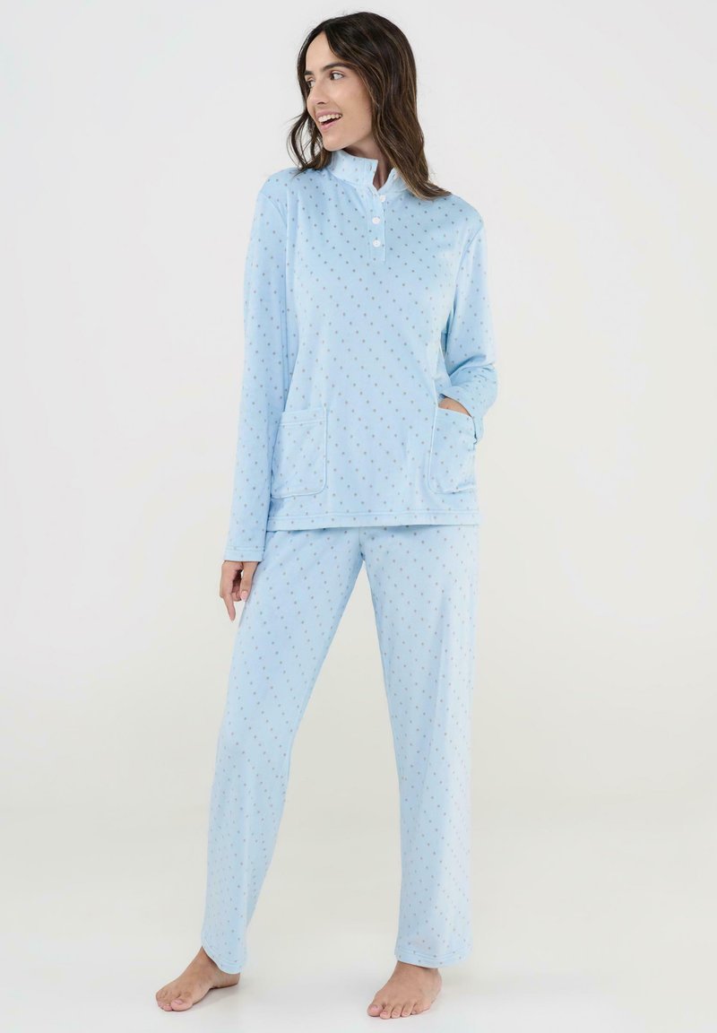 Conjunto de pijama azul claro que presenta una parte superior con cuello y tres botones, dos bolsillos frontales, y pantalones a juego decorados con un sutil patrón de lunares.