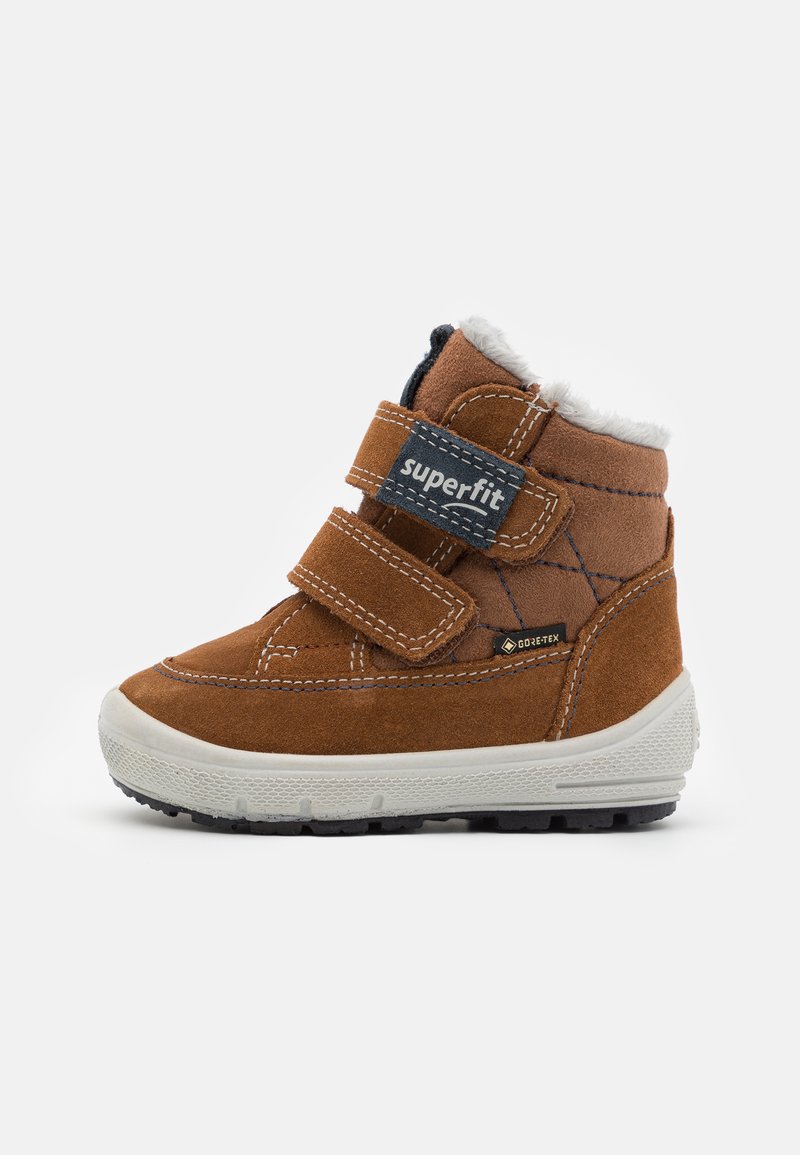 Bruine suède enkellaars met witte nepbont voering, twee verstelbare klittenbandbanden en zwarte rubberen zool. Heeft GORE-TEX-merken.