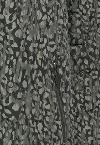 Pufjaka ar kviltojumu tumši zaļā un pelēkā leopardu rakstā, ar sānu rāvējslēdzēju un izšūtām dimanta detaļām. Strukturēta auduma.
