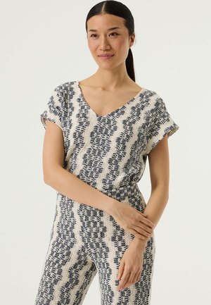 Patroongeprinte jumpsuit in roomwit en marineblauw, met een V-hals, korte mouwen en een textuurstof met een golvend ontwerp.