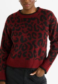 Red and black leopard print sweater, knitted fabric, crew neck, ribbed hem and cuffs, slightly loose fit, textured appearance.
