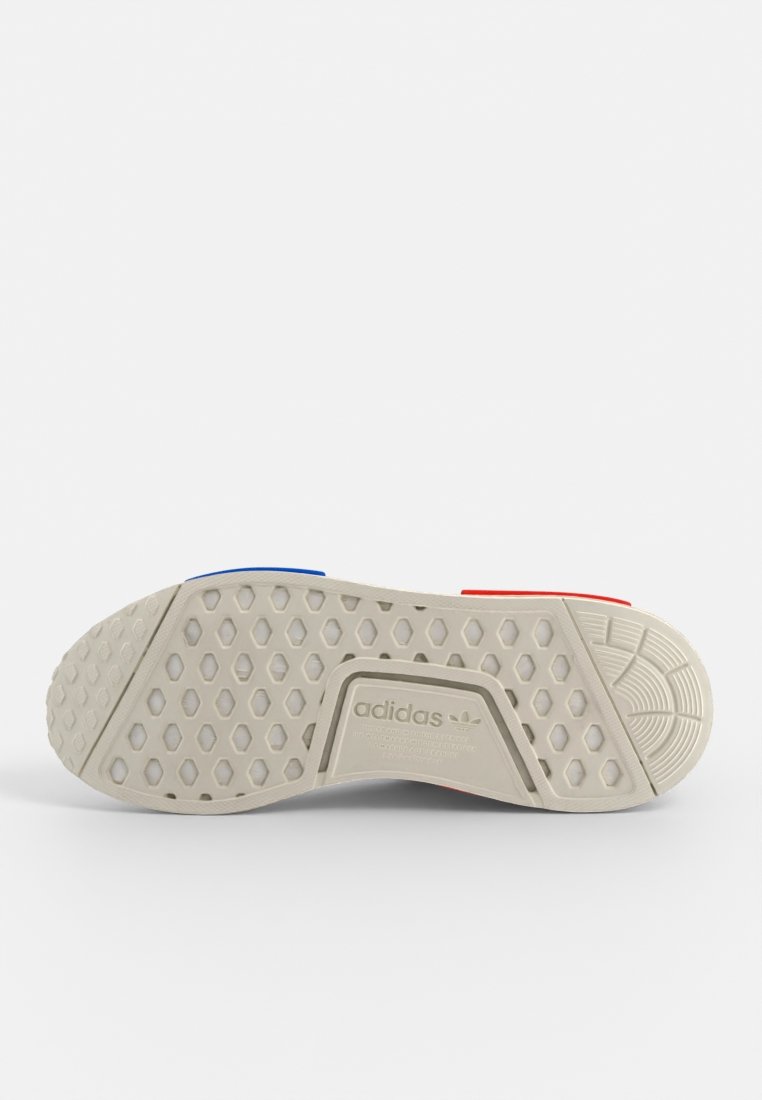 Adidas-Sneaker-Sohle, aus Gummi, hellgraue Farbe mit blauen und roten Akzenten, strukturiertes Muster, hexagonale und kreisförmige Designs.