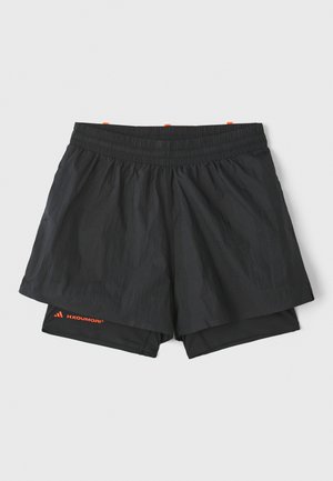 Shorts de sport noirs avec une taille élastique, doublure intérieure et panneaux latéraux perforés. Présente un logo orange sur le bas de la jambe.