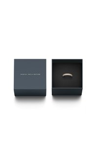 Rose gold ring with a curved design, set with clear crystals, displayed in a blue, rectangular box with a black interior and gold text.