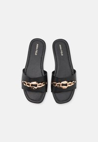 Svarta slidesandaler med glänsande yta, med en bred rem och en accent av guldkedja. Innersulan är vadderad med synlig sömnad.