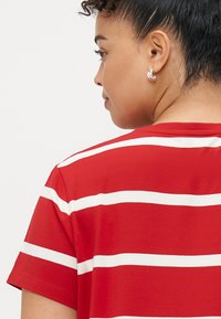 Κόκκινο T-shirt με λευκές οριζόντιες ρίγες, κοντά μανίκια και χαλαρή γραμμή. Μαλακό βαμβακερό υλικό με απαλό υφάσμα.